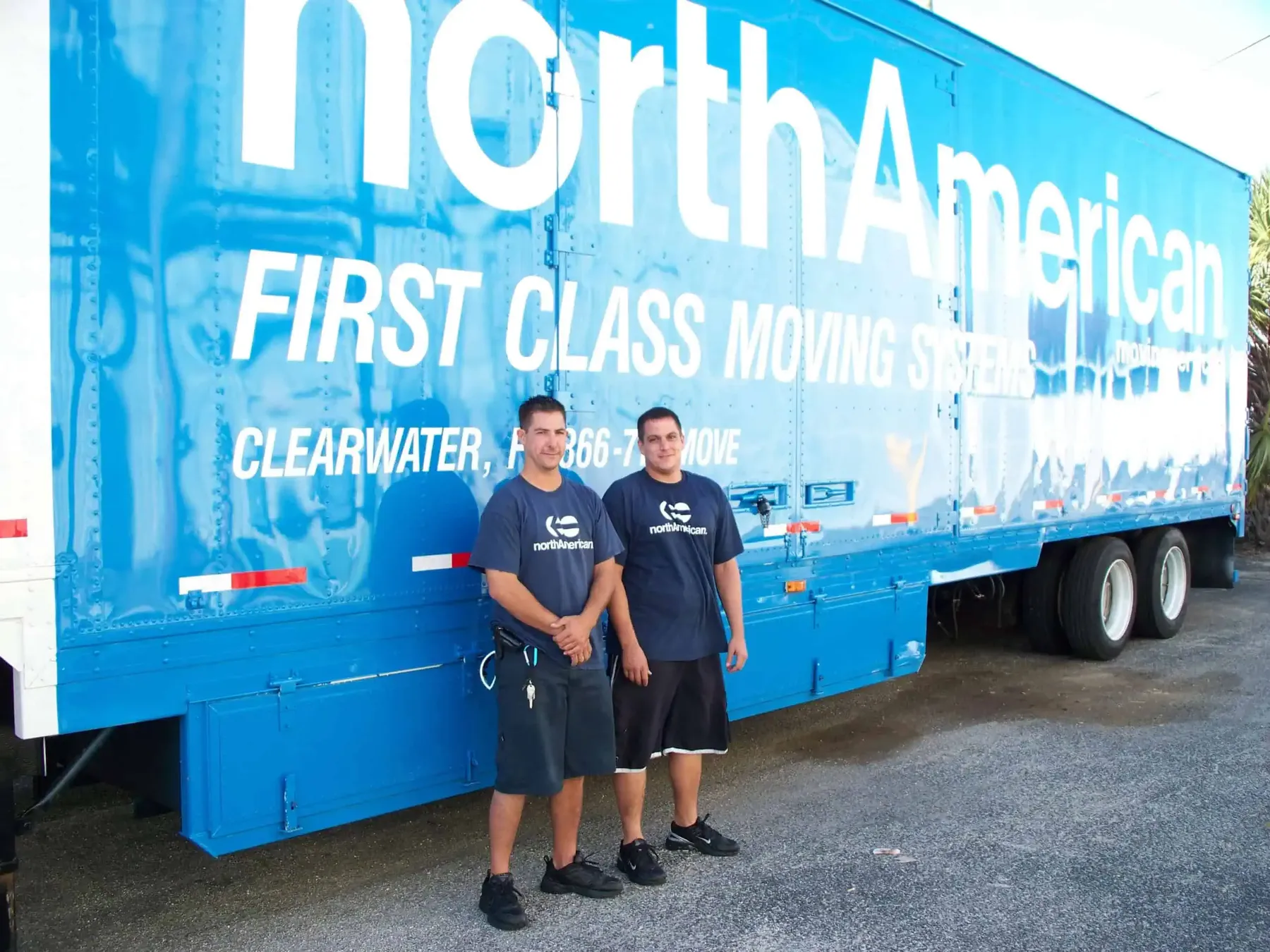 Two First Class movers in company shirts beside the truck