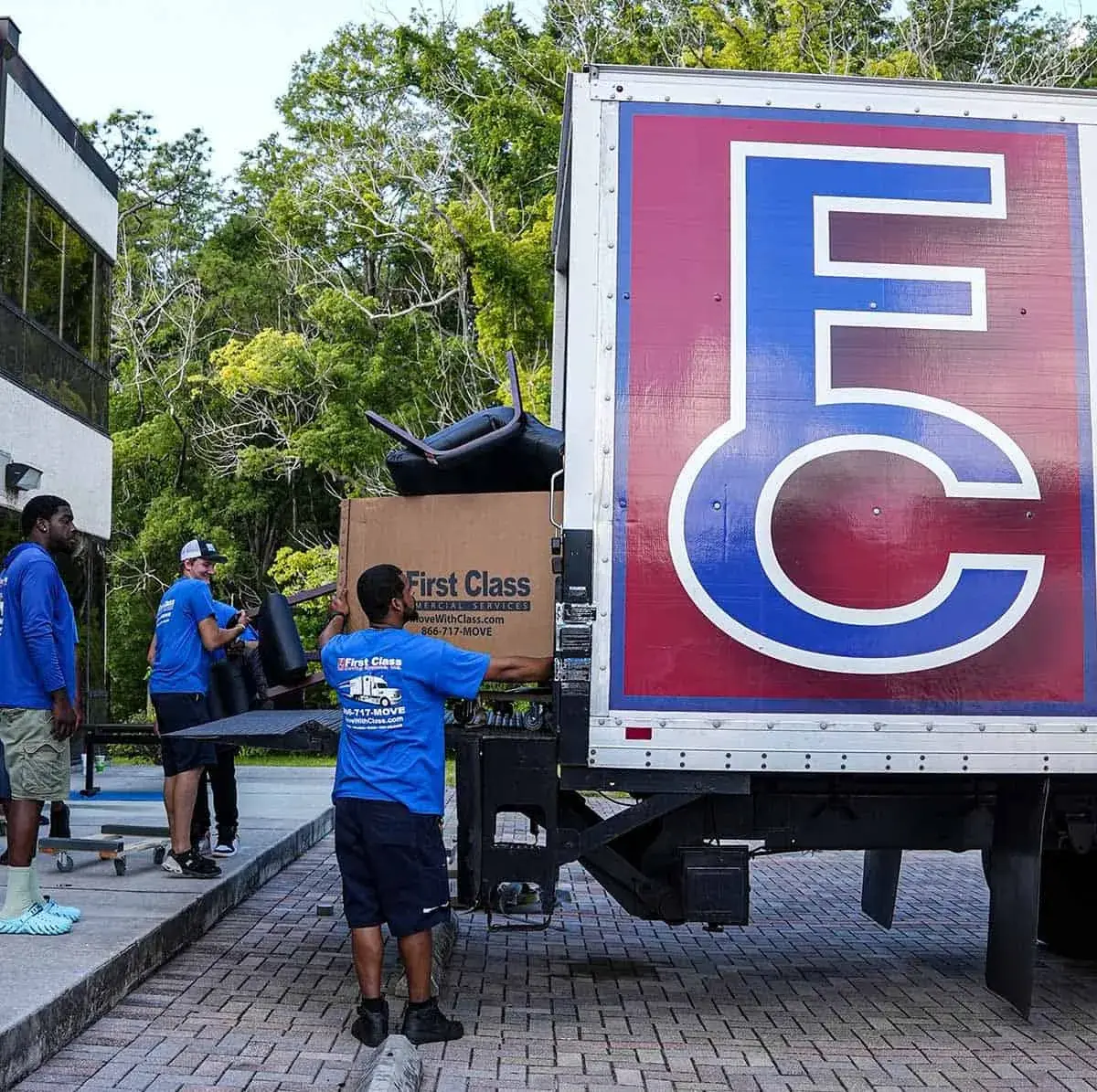 Crew member loading boxes beside the First Class truck