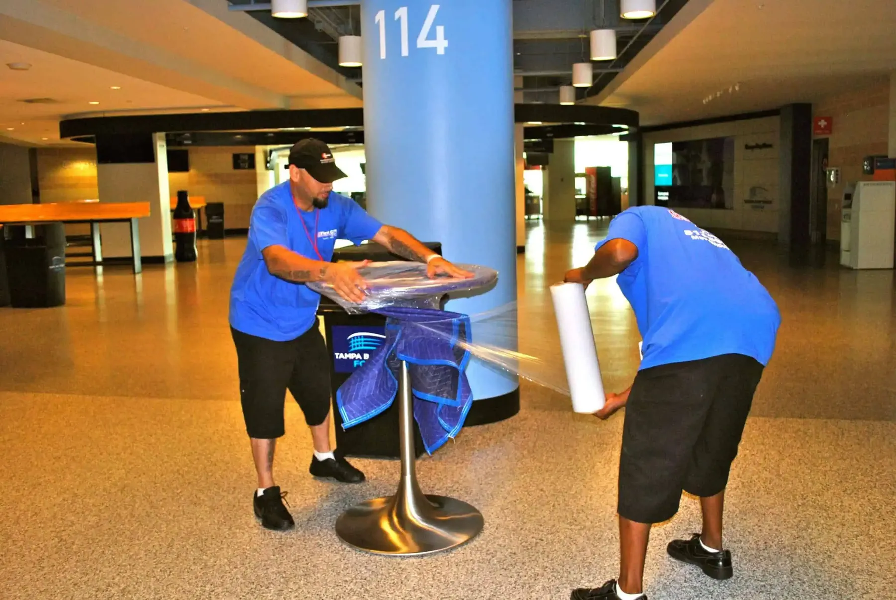 Crew shrink-wrapping a table during an arena move