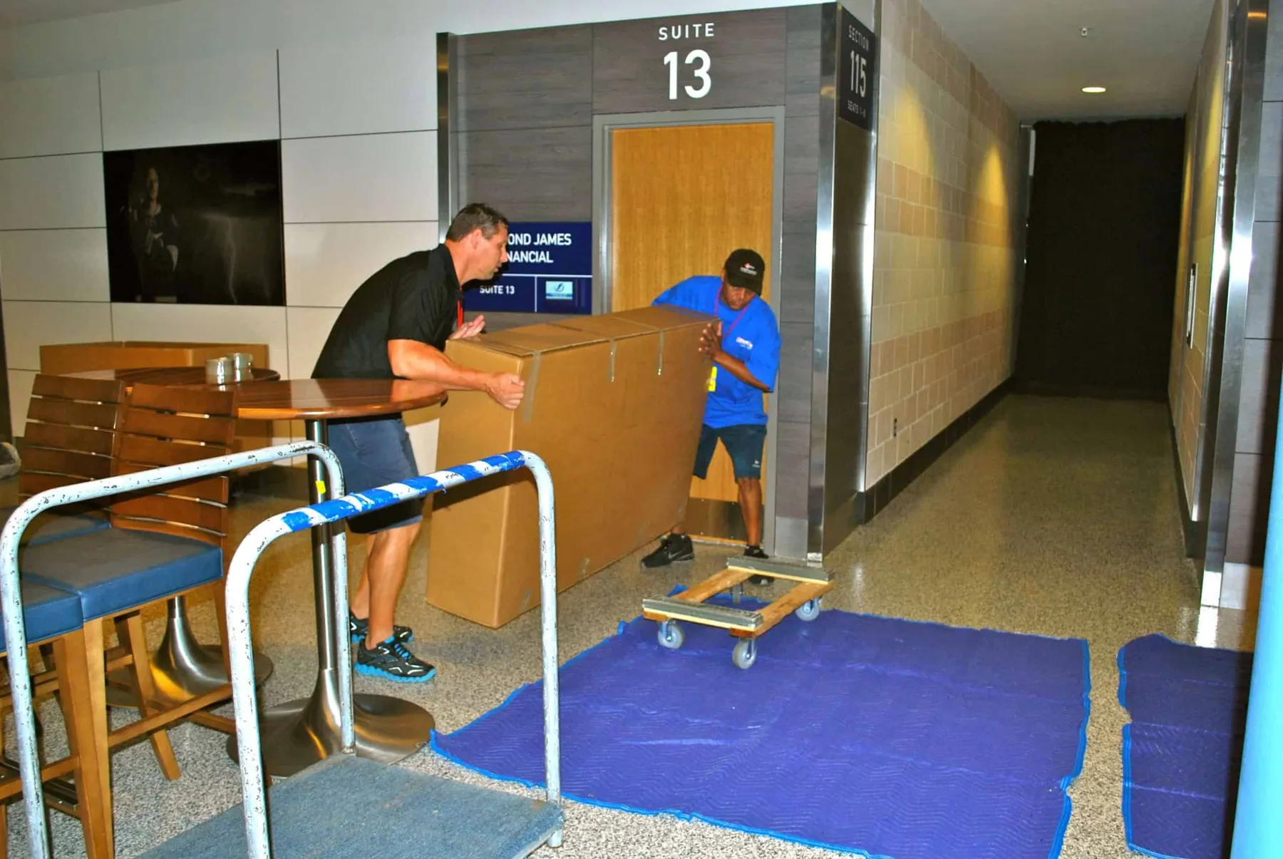 Crew moving a crate on a dolly in a suite